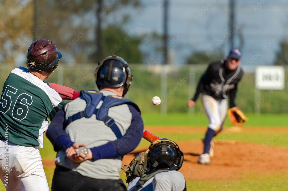 Men playing baseball game. Batter getting ready to hit a pitch during ballgame on a baseball diamond Men playing baseball game. Batter getting ready to hit a pitch during ballgame on a baseball diamond