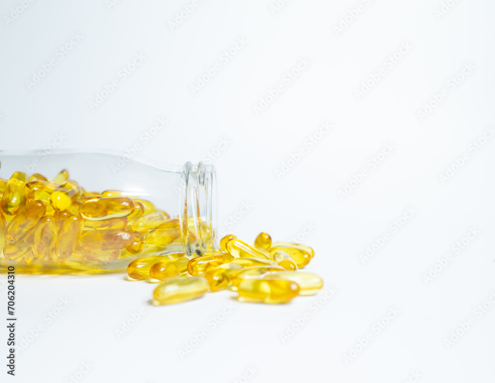 Fish Oil supplement capsules for health spill out from clear glass bottle with golden cap isolated on white background.