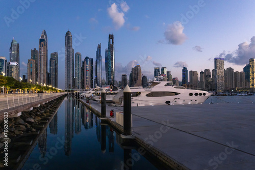 Beautiful view with modern skyscrapers  luxury yachts and water pier of Dubai Marina at sunset  United Arab Emirates