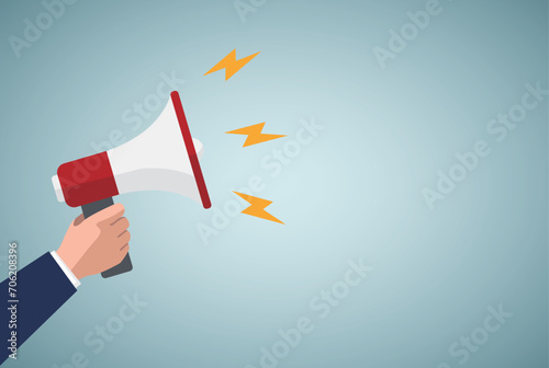 Hand holds a megaphone on a blue background. Concept of hiring, advertising, attention something. Banner. photo