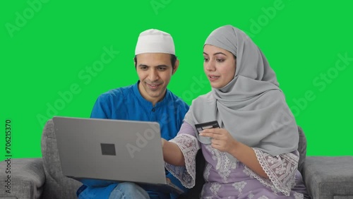 Muslim couple doing online shopping on laptop using credit card Green screen photo