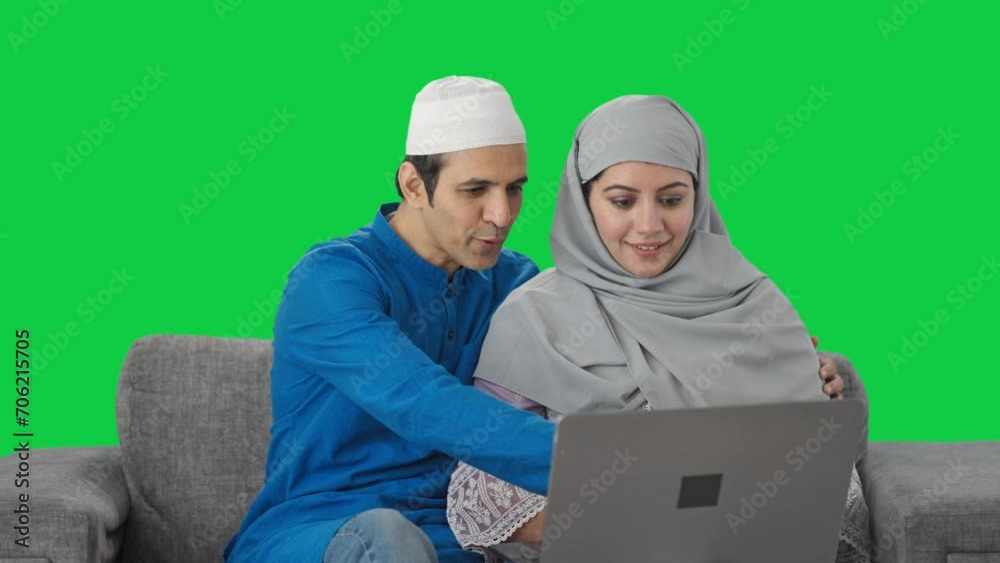 Happy Muslim couple doing shopping on laptop using credit card Green screen
