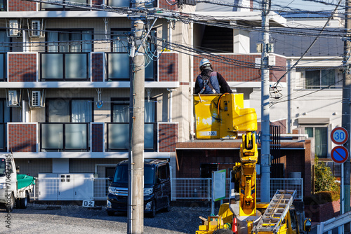 住宅街で電柱の上の電線の修理をする作業員 photo