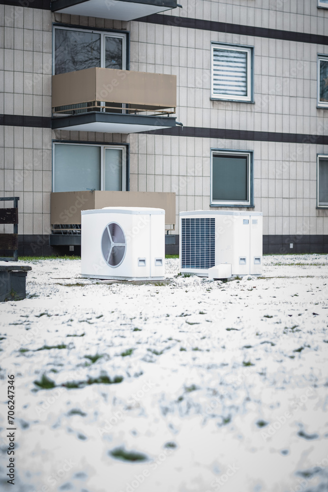 Zwei Wärmepumpen im Schnee auf einer Wiese vor einem Mehrfamilienhaus aus den siebziger Jahren, Düsseldorf, Deutschland Zwei Wärmepumpen im Schnee auf einer Wiese vor einem Mehrfamilienhaus aus den siebziger Jahren, Düsseldorf, Deutschland