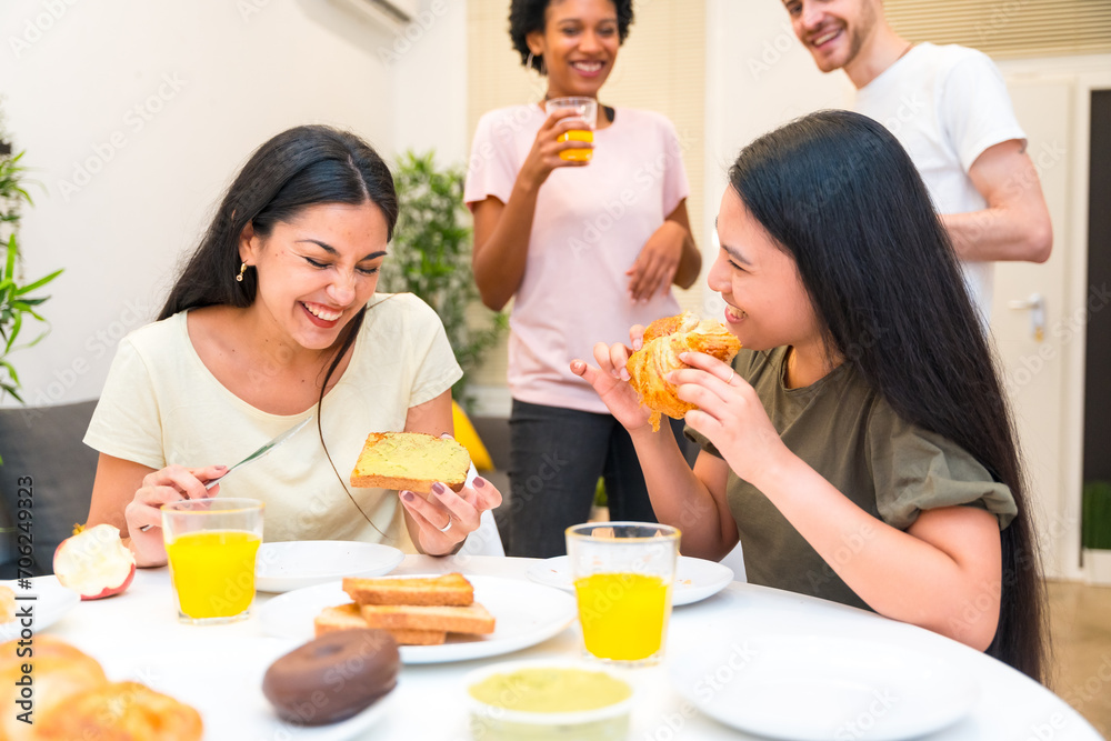 Friends laughing while having breakfast at home Friends laughing while having breakfast at home
