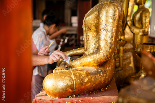 Close-up asian woman tourist Gilding gold leaf to Buddha for worship with faith to Buddha statue in temple thailand belief in Buddhism