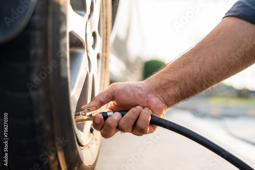 Man driver hand inflating tires. Fill Air station service for vehicle tires. Checking air pressure car wheels maintenance and safety photo