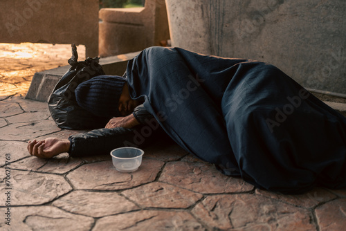 Homeless man on the street waiting for help food and money from people volunteer foundation donate. Poor tired stressed depressed hungry homeless man