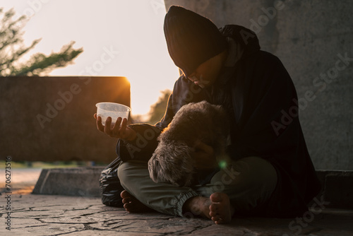Homeless man and dog on the street waiting for help food and money from people volunteer foundation donate. Poor tired stressed depressed hungry homeless man photo