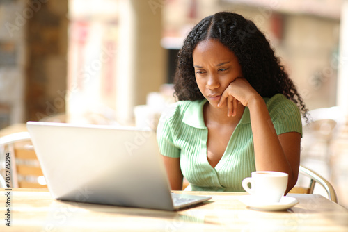 Serious black woman checking laptop in a bar photo