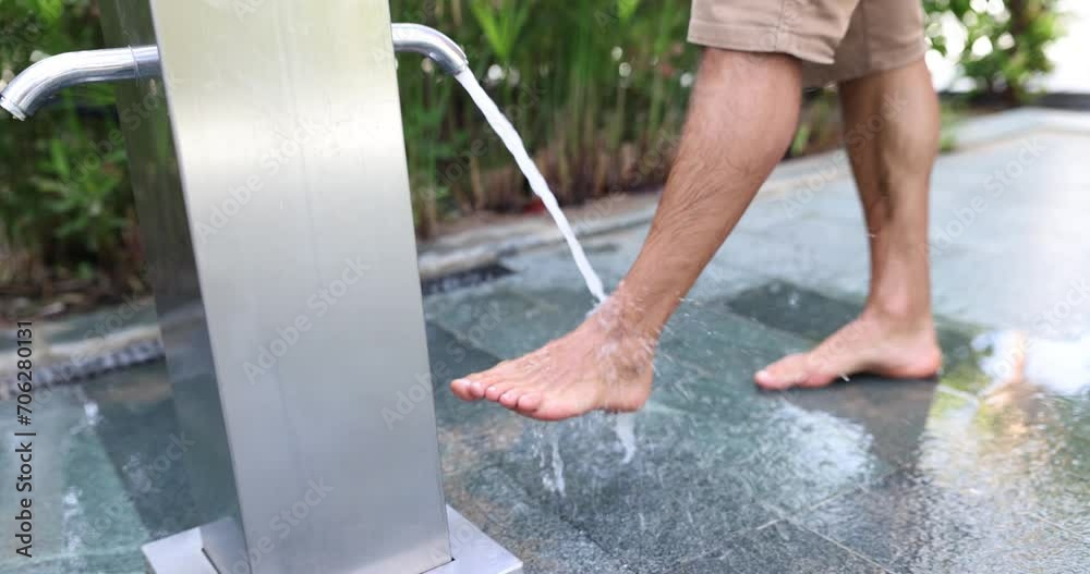 Man washing feet outdoors on beach. Foot washing by pool and hotel rules