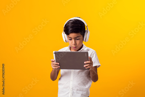 Kid boy with headphone and tablet playing video game. Leisure and gadget addiction concept