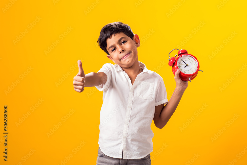 Kid boy holding alarm clock and showing thumb up gesture. Education and time management concept - obrazy, fototapety, plakaty 