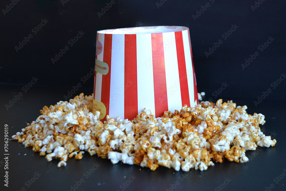 A striped bucket with flying popcorn isolated on a white background.