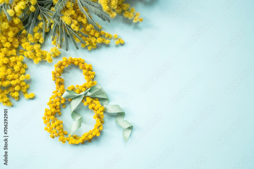 International Women's Day. A banner, a flyer, a beautiful postcard for March 8th. Yellow mimosa flowers in the shape of the number eight and a ribbon bow on a turquoise, blue background. - obrazy, fototapety, plakaty 