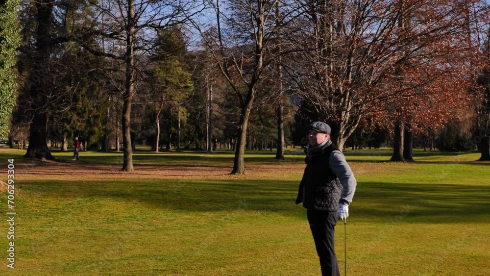 Elegant Male Golfer Hitting the Golf Ball on the Fairway with Bare Trees in a Sunny Day in Autumn on Golf Course in Switzerland. Elegant Male Golfer Hitting the Golf Ball on the Fairway with Bare Trees in a Sunny Day in Autumn on Golf Course in Switzerland.