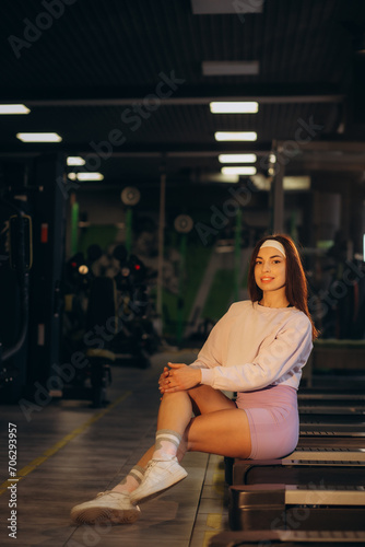 Nice commercial portrait of fit fitness female athlete smiling casual at the gym near machine treadmill