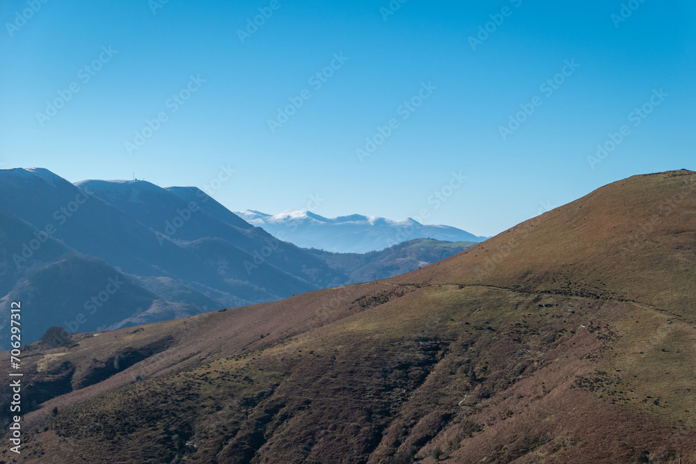 Montanhas em Artzamendi em Itxassou no País Basco com algumas trilhas de terra batida sobre a mesma e alguma neve ao fundo nos picos das montanhas
