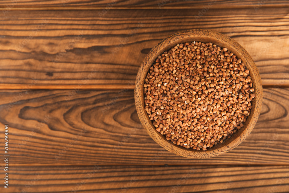 Raw buckwheat in a bowl on a textured wooden background. Wheat grains, porridge, cereals, raw buckwheat in a plate. Healthy food. Porridge. Diet. Organic cerea. Space for text.Copy space. Raw buckwheat in a bowl on a textured wooden background. Wheat grains, porridge, cereals, raw buckwheat in a plate. Healthy food. Porridge. Diet. Organic cerea. Space for text.Copy space.