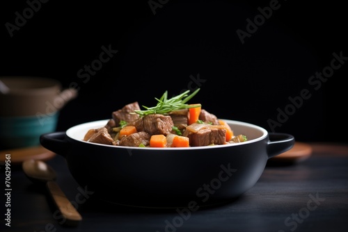 thick beef stew in a black bowl, dark moody lighting