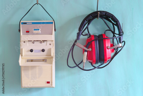 vintage cassette tape recorder and old red headphone on pastel green background.