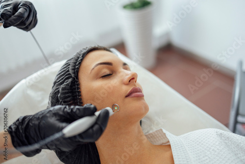 Beautiful caucasian young woman is doing a mole removal procedure in a modern beauty cosmetic dermatological clinic