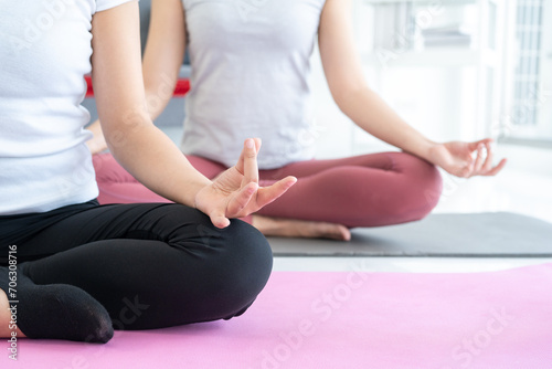 Two Young beautiful asian sport women sitting on the yoga mat practicing meditation. Fitness or exercise at home. Beautiful females relaxing after workout.