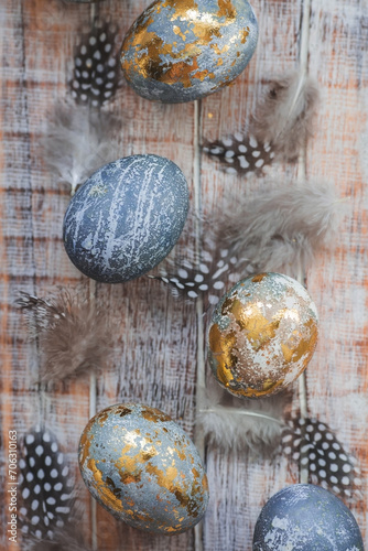 Happy Easter 2024. Stylish grey Easter eggs in the color of marble, concrete, gold and beautiful feathers on a wooden background. Egg coloring with natural dye karkade tea. Easter 2024.