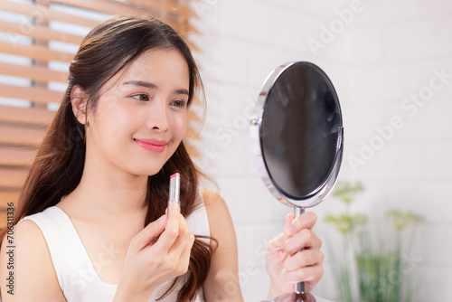 Beauty Asian woman using lipbalm in bedroom interior, lady taking care of her beautiful lips,
