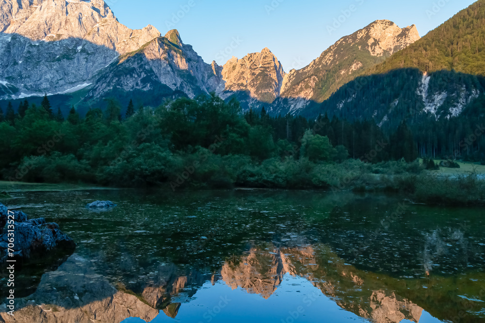 Morning sunrise view of Superior Fusine Lake (Laghi di Fusine) with majestic Mount Mangart in background in Tarvisio, Friuli Venezia Giulia, Italy. Captivating Water Reflection in tranquil atmosphere