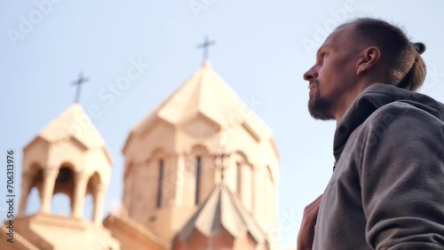 Side view, a handsome young man with a fashionable hairstyle crossed himself in a Christian manner, looking at the Christian temple and bowed. gesture of crossing one's fingers. Religion Concept