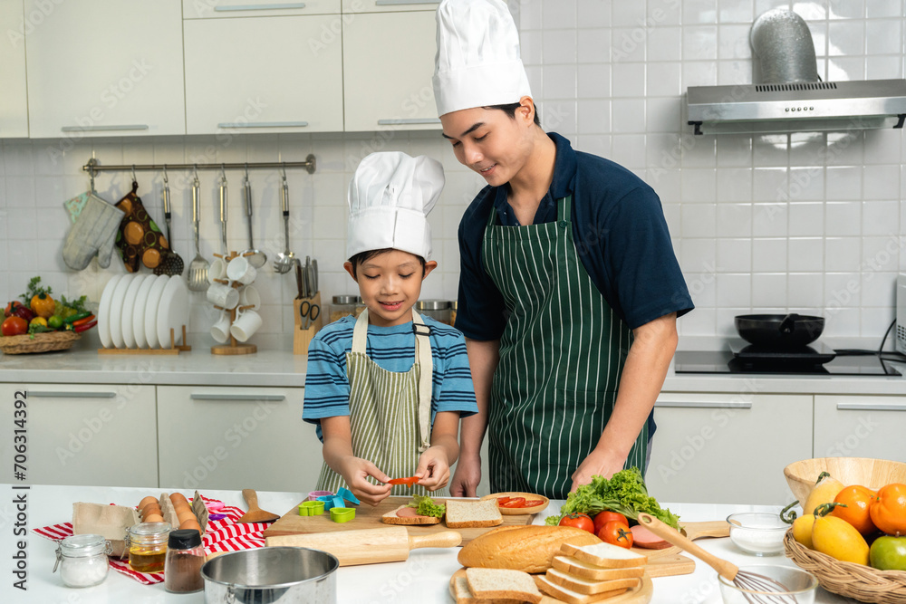 Happy moment asian father and son cooking breakfast in the kitchen. Dad and child asian family having fun preparing food bread egg sandwich. Positive parent and kid nice relationship