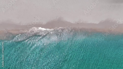 The drone is flying topdown going up above the shorline with crystal clear aqua blue water ocean and a white beach in Curacao Aerial Footage 4K photo