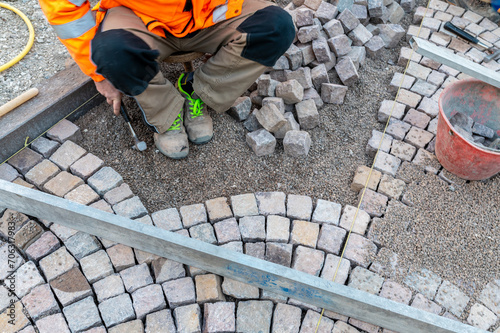 Resurfacing the road surface, manual laying of porphyry cubes on the road. Paving realized with red Trentino Porphyry cubes, Trentino Alto Adige, Italy