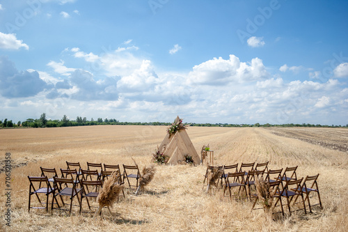 Triangular wooden arch in a golden field. Venue for wedding ceremony. Rustic style