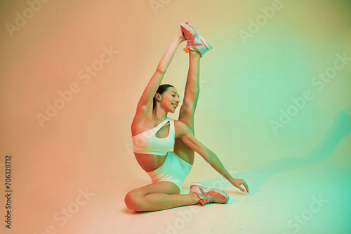 Flexible body type. Young fitness woman in sportive clothes against background in studio