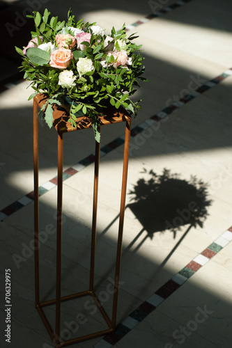 Flower arrangement of roses, eustoma, and other flowers as an element of decor on a golden centerpiece. photo