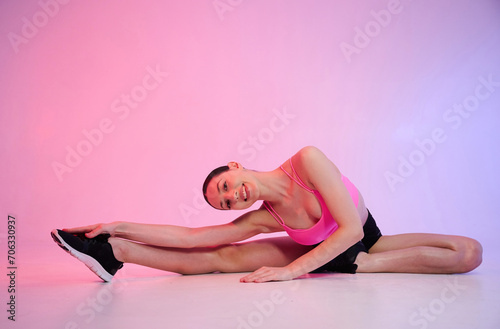 Futuristic lighting. Young fitness woman in sportive clothes against background in studio