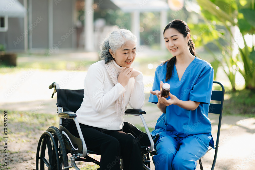 Elderly asian senior woman on wheelchair with Asian careful caregiver and encourage patient, walking in garden. with care from a caregiver. and senior health insurance Elderly asian senior woman on wheelchair with Asian careful caregiver and encourage patient, walking in garden. with care from a caregiver. and senior health insurance