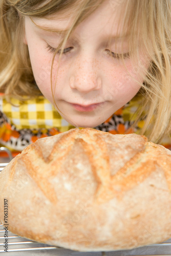 Young Girl Smelling a Loaf of Bread
 photo