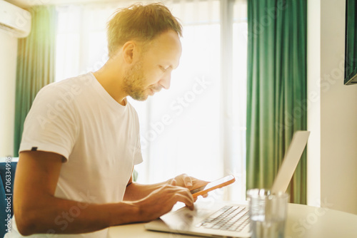 Man working at laptop at home office, distance job or online shopping, making purchases in internet stores.
