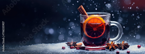 Close up photography of mulled vine in glass with cinnamon spices, orange and christmas background