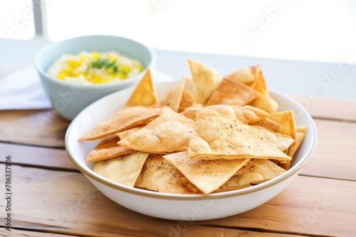 baked pita chips in bowl with side of garlic hummus