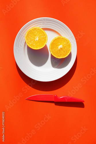 Halved Orange on Plate with Knife
