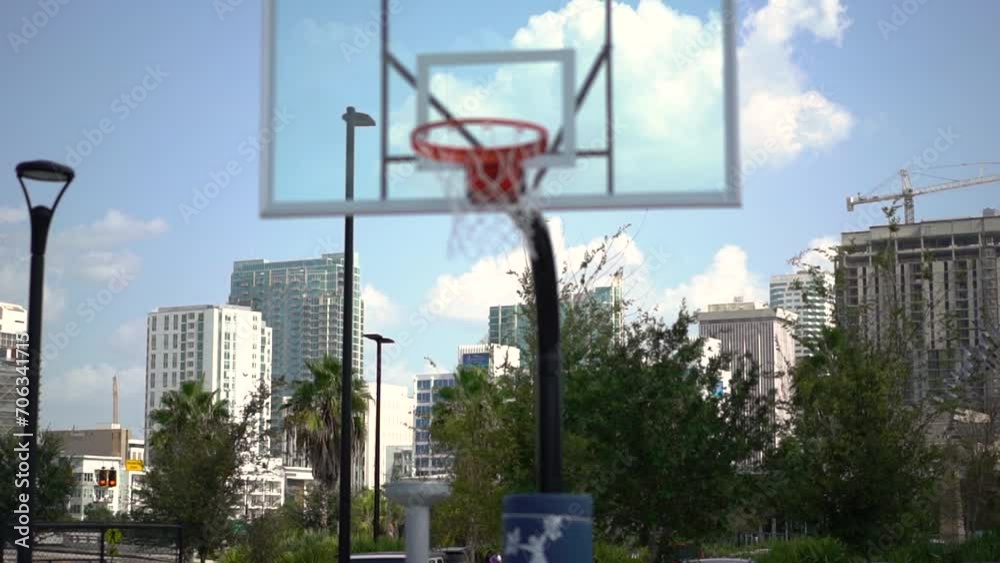 Downtown cityscape business district skyscrapers in the distance panning across bokeh basketball court hoop foreground Downtown cityscape business district skyscrapers in the distance panning across bokeh basketball court hoop foreground