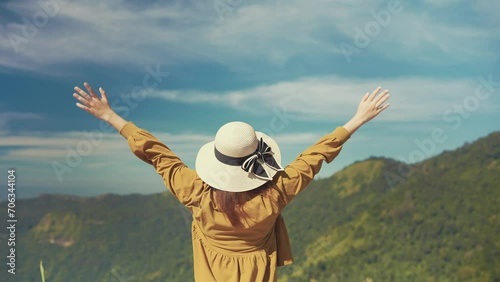 Young asian female tourist raised hands into breathing the fresh air looking at beautiful mountain view. Woman traveler stands alone with open arms in mountains. Natural beauty. Travel concept photo