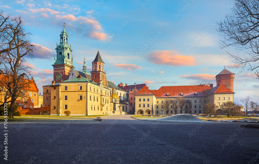 Wawel castle in Krakow, Poland. Panoramic view. Towers of Catholic temple. Picturesque territory and buildings architecture. Winter day with evening warm sunshine lighting. Sky dramatic clouds