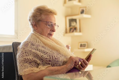 Senior woman in shawl using smart phone at home
 photo