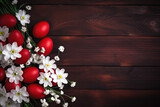 Easter dark red eggs and spring white flowers on dark wooden table, top view