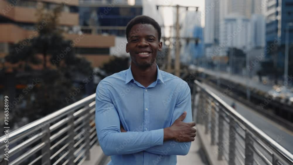 Portrait of the Young Successful Businessman Posing for the Camera Standing Outside, Wearing a Blue Shirt with Crossed Arms. Handsome Boss Outdoors Looking at the Camera. People and Business Concept Portrait of the Young Successful Businessman Posing for the Camera Standing Outside, Wearing a Blue Shirt with Crossed Arms. Handsome Boss Outdoors Looking at the Camera. People and Business Concept